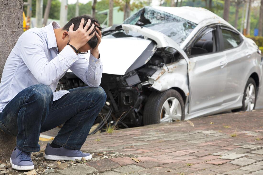 man sitting beside the damaged car